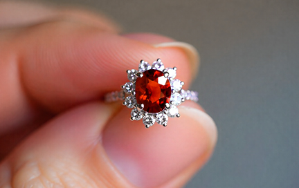 A close-up of a woman’s finger wearing a hessonite garnet ring.