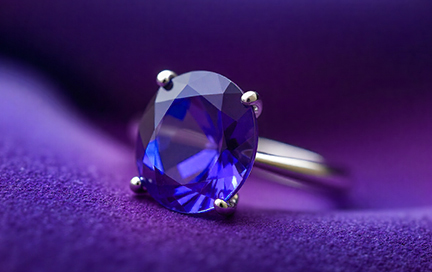 A close-up of a white gold tanzanite ring placed on deep velvet fabric.