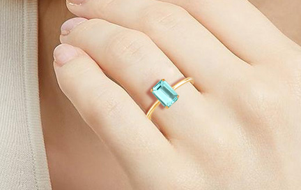 A woman showing a solitaire Paraiba tourmaline ring.