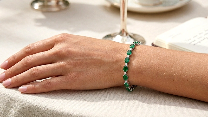 woman’s wrist adorned with emerald and diamond bracelet