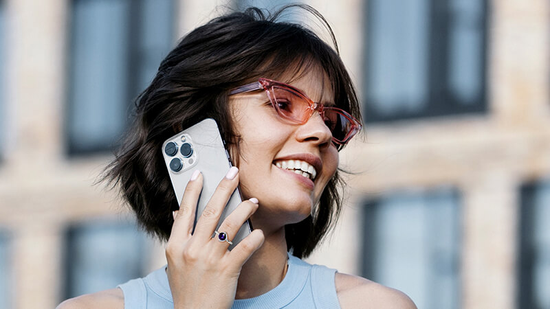 woman holding a silver or purple iPhone wearing a blue spinel ring
