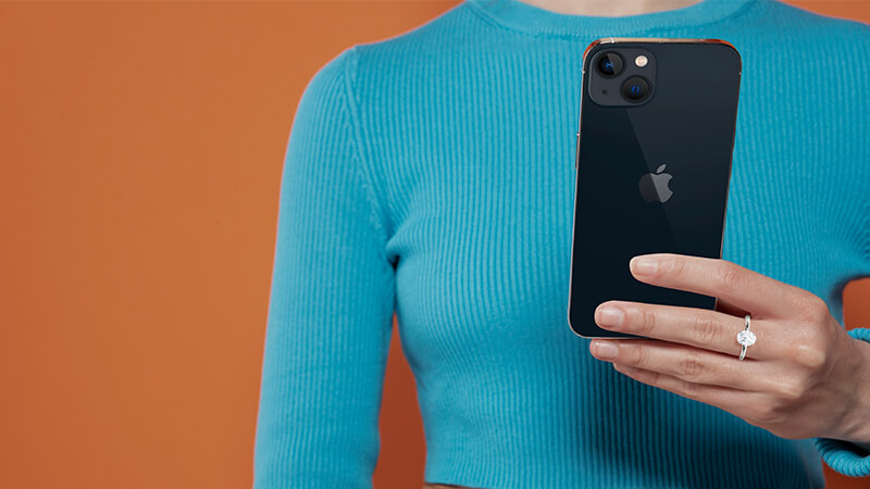 a woman holding a black iPhone wearing a diamond ring 